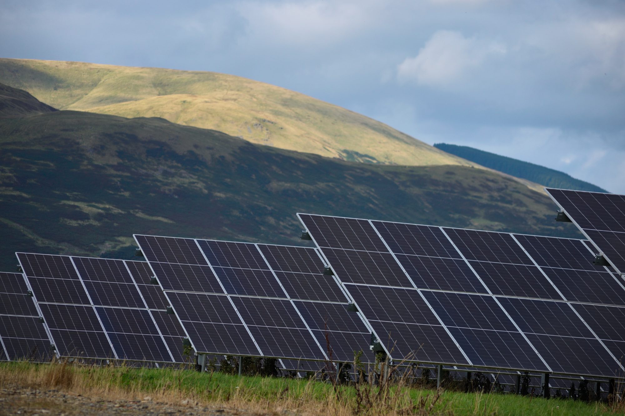 Rows of solar panels below a hillside